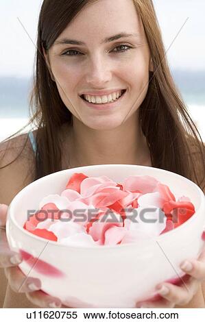 Stock Photography - Woman holding a bowl of rose petals. Fotosearch