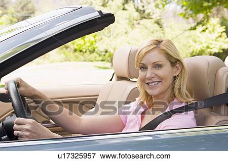 Stock Photo - Woman in convertible car smiling. Fotosearch