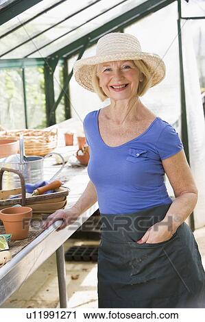 Stock Image - Woman in greenhouse smiling. Fotosearch