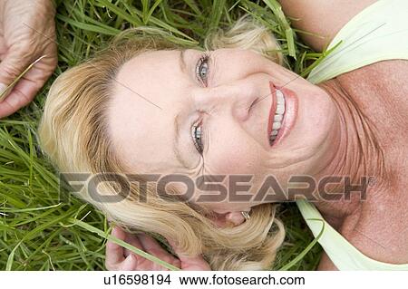 Picture - Woman lying in grass smiling. Fotosearch