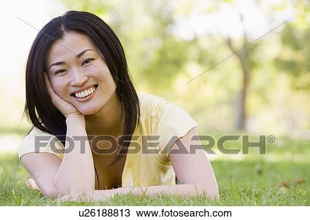 Stock Image - Woman lying outdoors smiling. Fotosearch