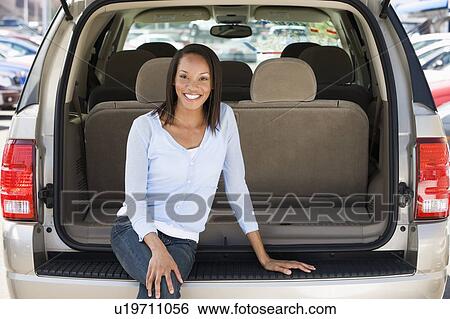 Stock Photograph - Woman sitting in back of van smiling. Fotosearch