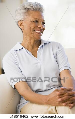 Woman sitting in living room smiling View Large Photo Image Stock Image - Woman sitting in living room smiling. Fotosearch