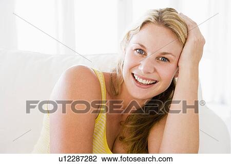 Stock Image - Woman sitting in living room. Fotosearch