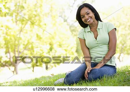 Stock Photo - Woman sitting outdoors smiling. Fotosearch