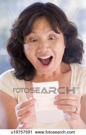 Stock Image - Woman with winning lottery ticket excited and smiling. Fotosearch