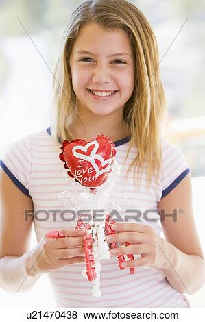 Stock Photo - Young girl on Valentine's Day holding love themed balloon smiling. Fotosearch