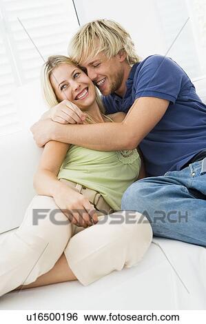 Stock Photograph - Couple in living room hugging and smiling. Fotosearch