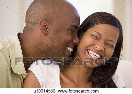 Stock Image - Couple in living room smiling. Fotosearch
