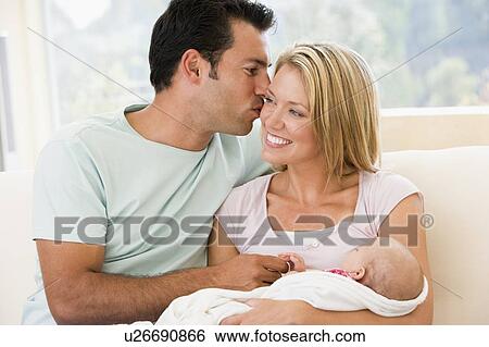 Stock Photograph - Couple in living room with baby smiling. Fotosearch