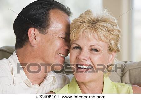 Stock Image - Couple relaxing in living room and smiling. Fotosearch