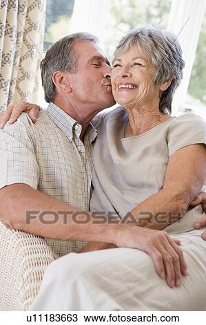 Couple relaxing in living room kissing and smiling View Large Photo Image Stock Image - Couple relaxing in living room kissing and smiling. Fotosearch