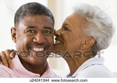 Picture - Couple relaxing indoors kissing and smiling. Fotosearch