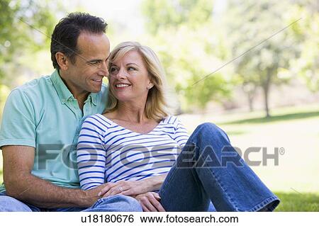 Stock Photograph - Couple relaxing outdoors in park smiling. Fotosearch