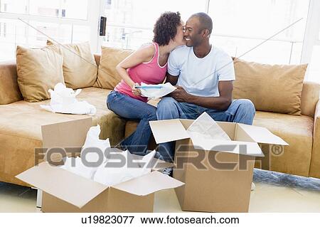 Couple unpacking boxes in new home kissing and smiling View Large Photo Image Stock Photo - Couple unpacking boxes in new home kissing and smiling. Fotosearch