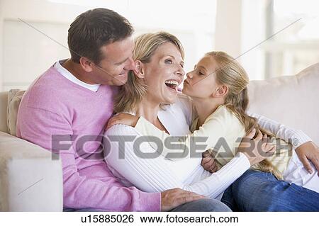 Stock Photograph - Family in living room with young girl kissing woman. Fotosearch