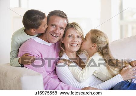 Family sitting in living room kissing and smiling View Large Photo Image Stock Photo - Family sitting in living room kissing and smiling. Fotosearch