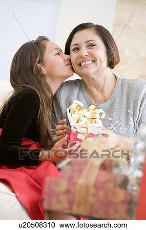 Granddaughter Kissing Grandmother On The Cheek, And Giving Her A Christmas Gift View Large Photo Image Stock Image - Granddaughter Kissing Grandmother On The Cheek, And Giving Her A Christmas Gift. Fotosearch