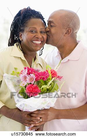Husband and wife holding flowers kissing and smiling View Large Photo Image Stock Photography - Husband and wife holding flowers kissing and smiling. Fotosearch