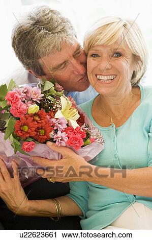 Husband giving wife flowers kissing and smiling View Large Photo Image Stock Image - Husband giving wife flowers kissing and smiling. Fotosearch