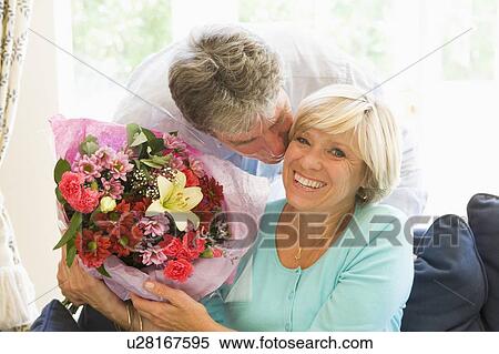 Stock Photography - Husband giving wife flowers kissing and smiling. Fotosearch
