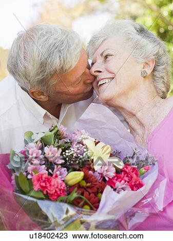 Husband giving wife flowers outdoors kissing and smiling View Large Photo Image Stock Image - Husband giving wife flowers outdoors kissing and smiling. Fotosearch
