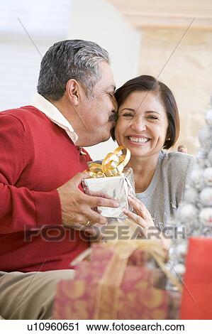 Middle Aged Couple Affectionately Sitting And Holding Christmas Present View Large Photo Image Stock Image - Middle Aged Couple Affectionately Sitting And Holding Christmas Present. Fotosearch