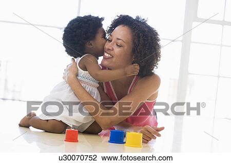 Mother and daughter indoors kissing and smiling View Large Photo Image Stock Image - Mother and daughter indoors kissing and smiling. Fotosearch