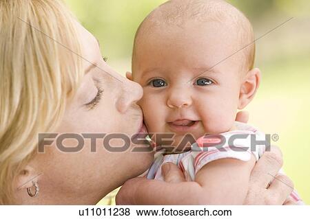 Stock Photo - Mother kissing baby outdoors. Fotosearch