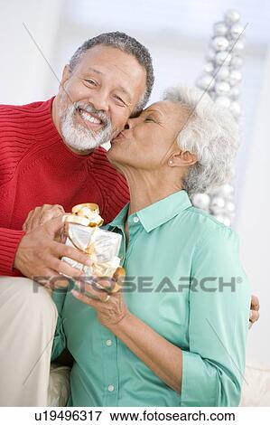Stock Photo - Senior Couple Exchanging A Christmas Gift. Fotosearch