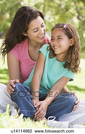 Woman and young girl sitting outdoors smiling View Large Photo Image Stock Image - Woman and young girl sitting outdoors smiling. Fotosearch