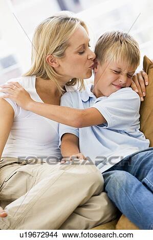 Woman kissing disgusted young boy in living room View Large Photo Image Picture - Woman kissing disgusted young boy in living room. Fotosearch