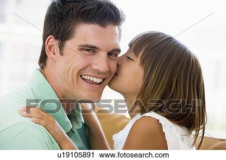 Young girl kissing smiling man in living room View Large Photo Image Stock Image - Young girl kissing smiling man in living room. Fotosearch