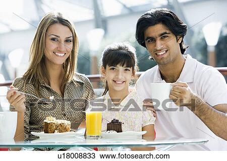 Stock Image - Family at restaurant eating dessert and smiling (selective focus). Fotosearch
