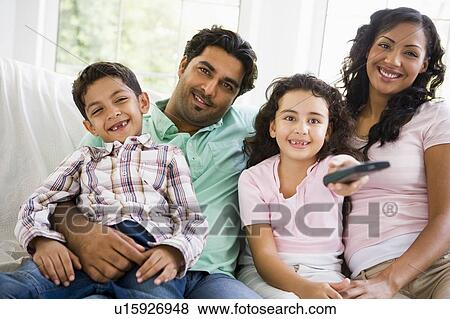Family in living room with remote control smiling (high key/selective focus) View Large Photo Image Stock Photo - Family in living room with remote control smiling (high key/selective focus). Fotosearch