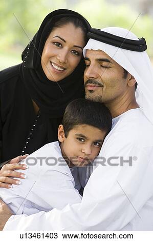 Stock Image - Family outdoors in park embracing and smiling (selective focus). Fotosearch
