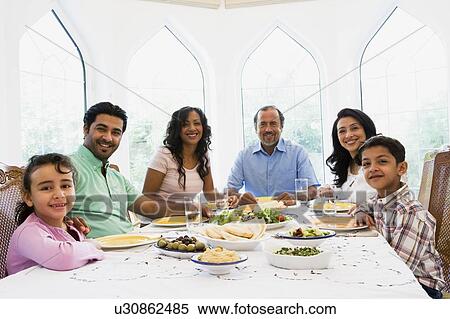 Family sitting at dinner table smiling (high key) View Large Photo Image Stock Photography - Family sitting at dinner table smiling (high key). Fotosearch