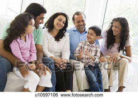 Stock Photograph - Family sitting in living room smiling (high key). Fotosearch