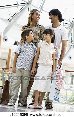 Stock Photograph - Family standing in mall smiling (selective focus). Fotosearch