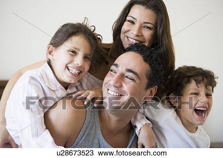 Stock Image - Family together on bed in bedroom smiling (selective focus). Fotosearch
