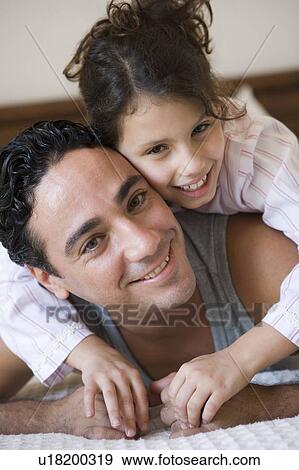 Stock Photo - Father and daughter girl relaxing on bed in bedroom smiling (selective focus). Fotosearch