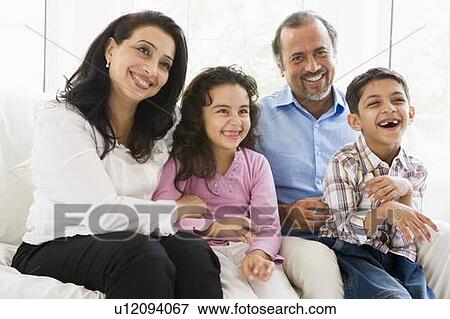 Stock Photo - Grandparents sitting in living room with grandchildren smiling (high key). Fotosearch