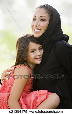 Stock Photography - Mother and daughter outdoors in park embracing and smiling (selective focus). Fotosearch