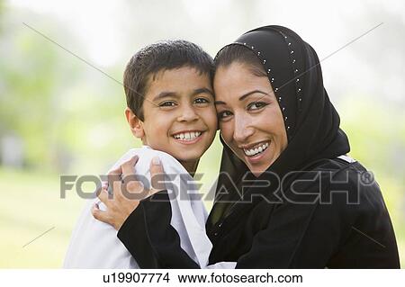Picture - Mother and son outdoors in park embracing and smiling (selective focus). Fotosearch