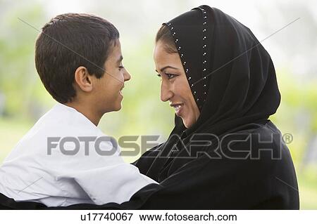 Mother and son outdoors in park embracing and smiling (selective focus) View Large Photo Image Stock Photo - Mother and son outdoors in park embracing and smiling (selective focus). Fotosearch