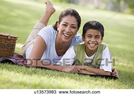 Stock Image - Mother and son outdoors in park with picnic smiling (selective focus). Fotosearch