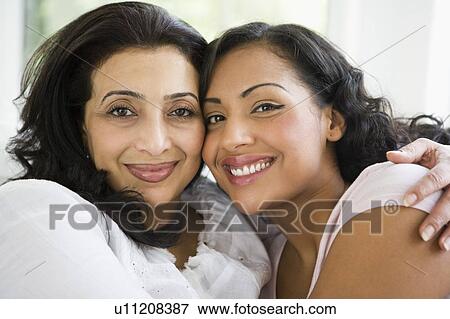 Two women in living room embracing and smiling (high key) View Large Photo Image Stock Photo - Two women in living room embracing and smiling (high key). Fotosearch