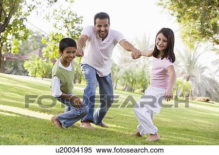 Two young children outdoors in park pulling smiling father by arms (selective focus) View Large Photo Image Stock Photography - Two young children outdoors in park pulling smiling father by arms (selective focus). Fotosearch