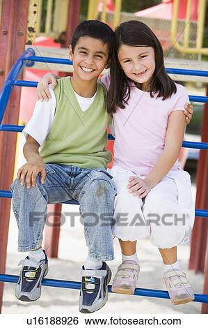 Two young children sitting on playground structure smiling (selective focus) View Large Photo Image Stock Photograph - Two young children sitting on playground structure smiling (selective focus). Fotosearch