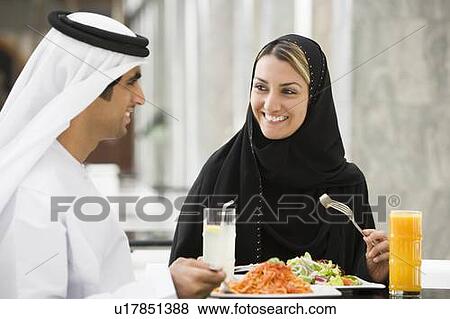Couple at restaurant eating and smiling (selective focus) View Large Photo Image Stock Photo - Couple at restaurant eating and smiling (selective focus). Fotosearch